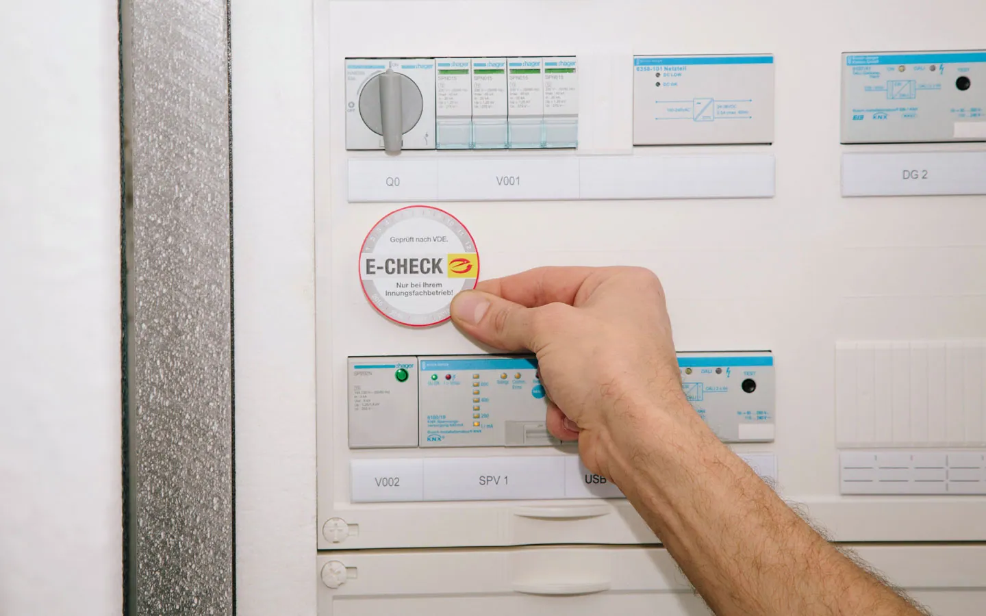 E-CHECK - Mitarbeiter klebt in der Verteilung die E-CHECK Plakette an &middot; ABE Elektrotechnik