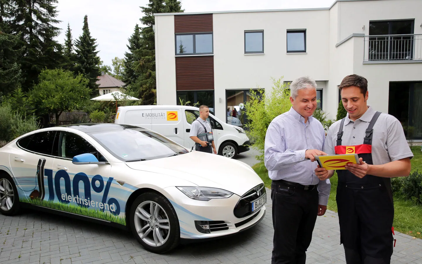 E-Mobilität - Mitarbeiter mit Kunden vor Elektrofahrzeugen 100% elektrisch &middot; ABE Elektrotechnik